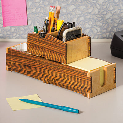 Desk caddy with dovetail joints holding pencils, tape measure, and sticky notes on a workbench.