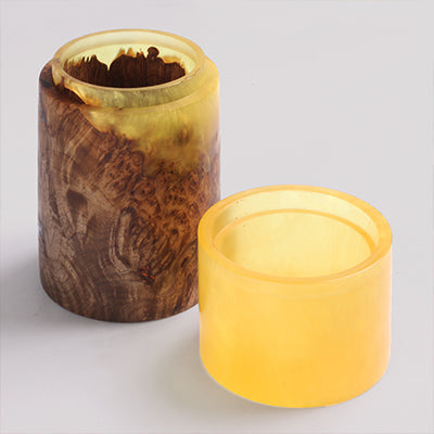 Turned box with wood burl body and translucent amber resin lid separated on white background