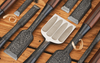 Set of Japanese woodworking chisels with patterned steel blades and wooden handles on wood surface with wood shavings.
