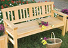 Outdoor wooden bench with slatted back and armrests, flowers on seat and grass background.