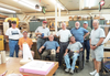 Group of men posing in a woodworking workshop with tools and wood pieces in the background