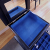 Open black jewelry armoire drawer lined with blue felt and attached mirror inside lid