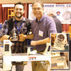 Two men shaking hands behind a JET wood lathe at a woodworking show booth, with inset close-ups of autographed lathe parts.