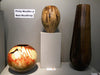 Three turned wooden vessels with varied shapes and finishes displayed on a pedestal and shelf.