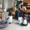 Woodworker adjusting dust collection system connected to shop vacuum and cyclone separator in workshop