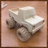 Handcrafted wooden toy truck with large treaded wheels on workshop table