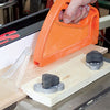 Hand using push block to guide wood through table saw fence and clamps in workshop