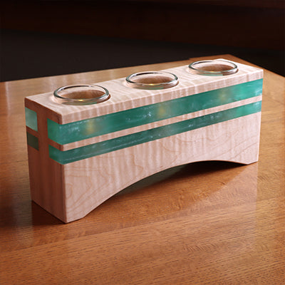 Curved maple wood tealight holder with turquoise resin inlays and three glass cups on wooden table